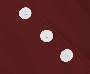 Close-up of white resin buttons on dark red woven fabric of the vintage Hepburn dress