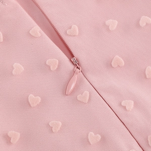 Détail de robe vintage rose montrant le jacquard en cœur et la fermeture éclair invisible