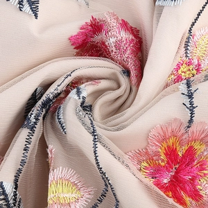 Detail of floral embroidery on nude mesh fabric with vibrant rose and yellow silk threads