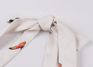 Dettaglio del tessuto dell'abito crema con stampa a farfalla su materiale in twill