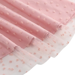 Détail d'une robe vintage rose avec motifs cœurs en relief et bordure en tulle blanc
