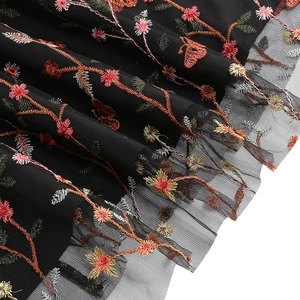 Detailed embroidery of colorful flowers and butterflies on black mesh of the V-neck gown