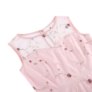 Détail de la broderie florale rose et de la maille transparente sur la robe rétro sans manches