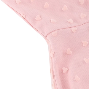 Détail d'une robe en tulle rose avec motifs de cœurs texturés et coutures de haute qualité