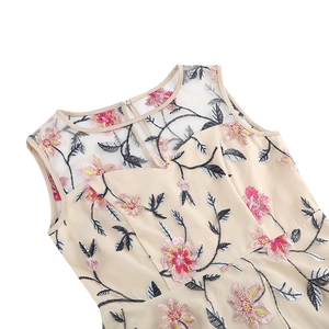 Détails de la broderie de fleurs roses et jaunes sur la robe vintage sans manches beige