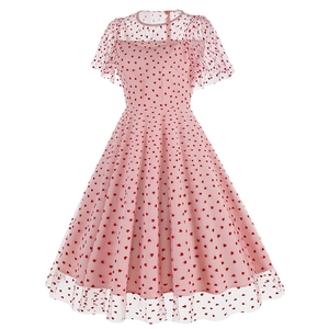 Détail d'une robe en maille rose avec taille cintrée et motifs de cœurs rouges