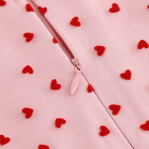 Gros plan sur tissu en maille rose avec broderie de cœurs rouges et fermeture invisible