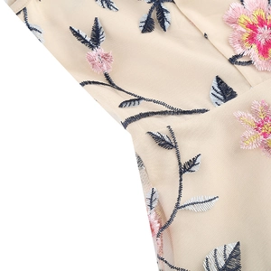 Détail de la broderie florale sur tissu en maille beige pour cette robe vintage