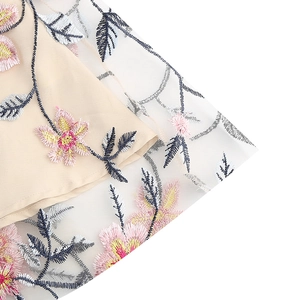 Détail de broderies florales délicates sur le tissu en tulle blanc de la robe