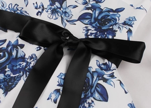 Dettaglio dell'abito floreale vintage anni '50 con cintura in raso nero annodata in vita