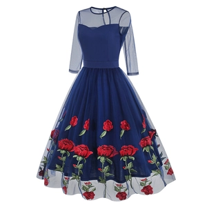 Détail de broderie de roses rouges sur la jupe en maille bleu marine de la robe