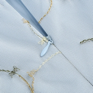 Détail de robe en tulle bleu clair avec broderie florale et fermeture éclair invisible