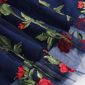 Gros plan détaillé sur la broderie de roses rouges sur robe de soirée en tulle bleu marine