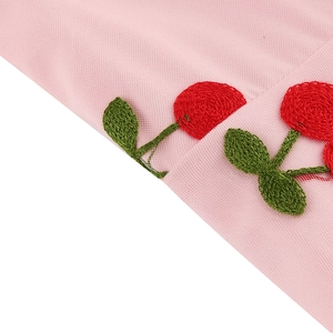 Détail de la broderie cerise rouge sur le tissu en tulle rose de cette robe rétro