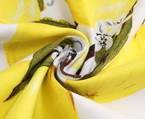 Detailed macro view of retro lemon print fabric with green leaves on white textile
