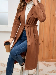Close-up of tan suede long trench coat with classic notched lapels and waist belt detail