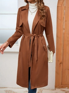 Detail of a brown suede long trench coat featuring a waist belt and large lapels