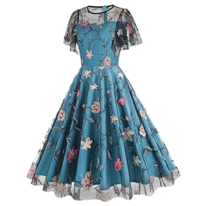 Detailed embroidery of pink and yellow flowers on dark green tulle dress with lace neckline