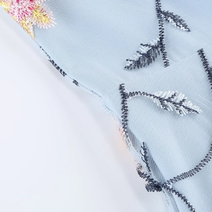 Gros plan détaillé de broderie florale colorée sur tissu en tulle bleu clair