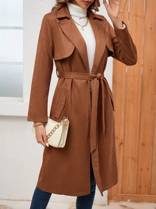 Detail of brown suede trench coat featuring waist tie belt and lapel collar design