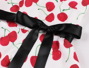 Vista dettagliata della stampa a ciliegie rosse con fiocco decorativo in raso nero in vita
