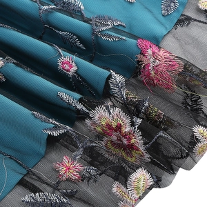 Detail of premium floral embroidery on mesh fabric over peacock blue lining of the dress
