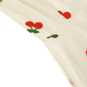 Détail de la broderie cerise rouge et fermeture éclair invisible sur une robe vintage