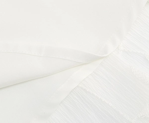 Makro-Detail von weißem Cocktailkleid mit feiner Stickerei und durchscheinender Wellengaze