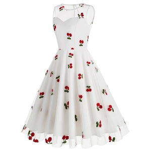 Gros plan sur le tissu en maille blanche avec broderies cerises rouges sur une robe rétro