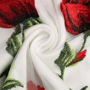 Détail macro de broderie de roses rouges sur tissu en maille blanche pour robe