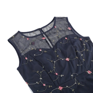 Gros plan détaillé des broderies florales rouges sur la robe vintage sans manches bleue