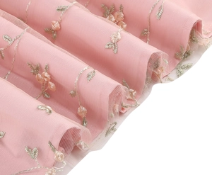Detail of delicate floral embroidery on pink tulle mesh fabric with satin inner lining