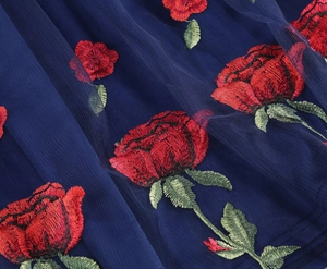 Close-up of delicate red rose embroidery on navy blue tulle fabric for cocktail dresses