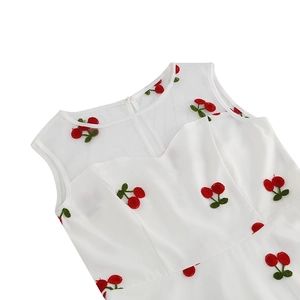 Détail de l'encolure en mesh blanc avec broderie cerise rouge sur la robe rétro