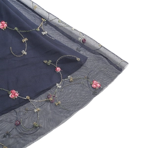 Détail de la broderie florale rouge sur le tissu en tulle bleu marine de la robe vintage