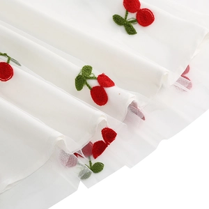 Détail du tissu en mesh blanc avec broderie de cerises sur une robe vintage des années 50