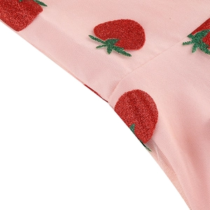 Détail du tissu en maille rose avec des motifs de fraises pailletées rouges brillants