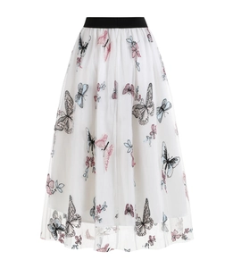 Détail des broderies papillons colorées sur le tissu en tulle blanc de la jupe