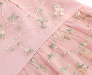 Detail of pink mesh dress featuring delicate floral embroidery and elegant pleated waistline