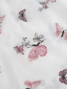 Gros plan de la broderie papillon complexe sur le tissu en tulle blanc de la jupe