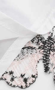 Détail en gros plan d'une broderie florale vintage sur un tissu en maille blanche