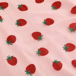 Détail du tissu en tulle rose brodé de fraises rouges scintillantes et de feuilles vertes