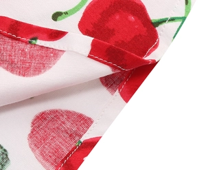 Macro shot of retro red cherry print on white cotton dress with double-stitched hem
