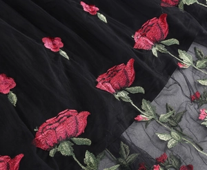 Close-up of intricate red rose embroidery on semi-transparent black mesh fabric