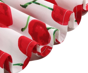 Detail of ruffle hem on white vintage dress featuring red cherry and green leaf print