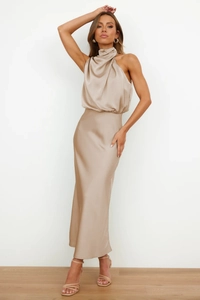 Detail of elegant champagne satin dress featuring a high-neck halter drape and smooth texture