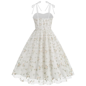 Detail of white mesh dress featuring delicate floral embroidery and adjustable bow straps