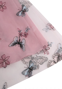Gros plan sur la jupe en tulle rose avec broderies de papillons bleus et fleurs