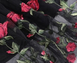 Detail of red rose embroidery and floral needlework on black sheer mesh vintage dress fabric