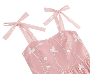 Nahaufnahme eines rosa Cocktailkleids mit floraler Stickerei und Schleifenträgern am Saum